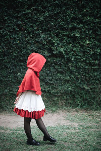 Rear view of girl with red umbrella standing on land