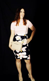 Portrait of smiling woman standing against black background