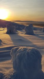 Scenic view of frozen landscape against sky during sunset