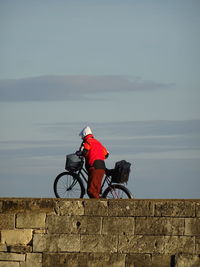 Man sitting by sea against sky