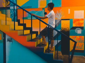 Side view of man climbing stairs by painted wall