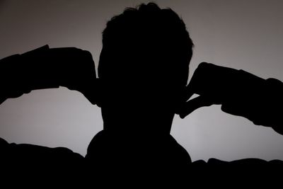 Silhouette man holding stick in front of mountains against black background