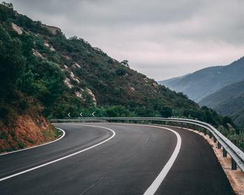 Road leading towards mountains against sky