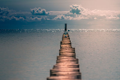 Surface level of wooden pier over sea against sky