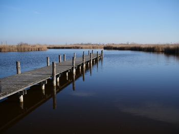 Wooden posts in lake against clear sky