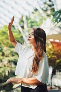 Young woman shielding eyes while standing by railing