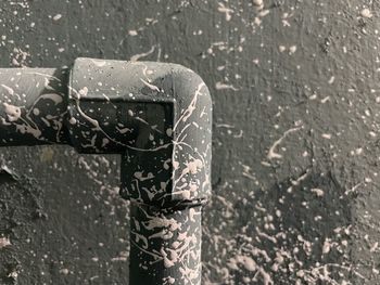 Close-up of water drops on metal against wall