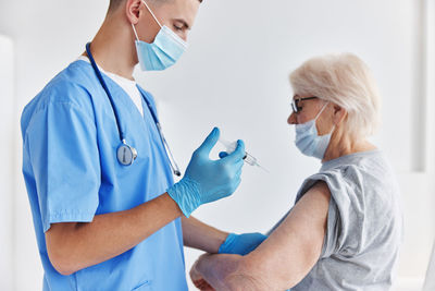 Doctor wearing mask vaccinating patient