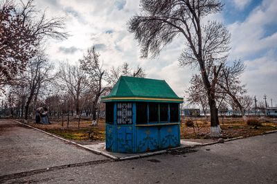 Built structure by bare trees against sky in city