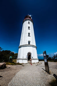 Low angle view of lighthouse by building against clear blue sky