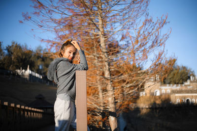 Woman standing by tree against sky