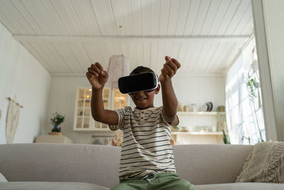 Portrait of young man using mobile phone while sitting on sofa at home