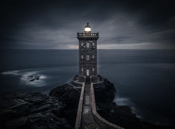 A mysterious lighthouse in france's brittany standing majestically on the rocky coastline at dusk