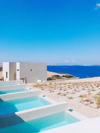 Swimming pool by sea against clear blue sky