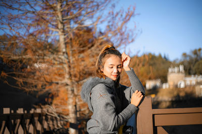 Portrait of woman standing by railing against trees