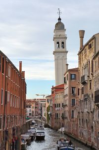 Canal amidst buildings in city against sky