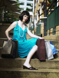 Full length of young woman sitting with shopping bags on steps