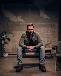 Portrait of man sitting on chair in abandoned building