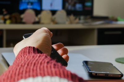 Cropped hand of woman holding mobile phone at home