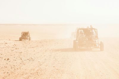 Buggies on barren landscape against clear sky