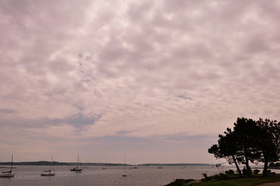 Boats in sea against cloudy sky