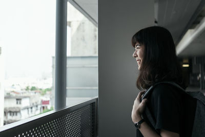 Portrait of a young woman looking through window