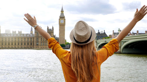 Traveler student girl with raised arms in london enjoying the view of mains attractions, uk