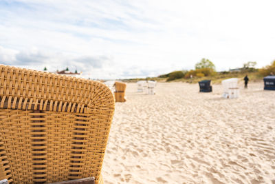 Hooded chairs on sand at beach against sky