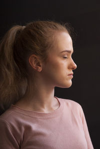 Close-up of young woman against black background