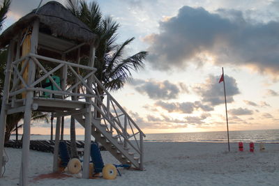 Lifeguard hut on beach against sky during sunset