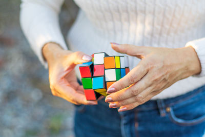Midsection of woman holding puzzle cube outdoors
