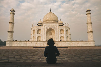 Young woman admiring taj mahal beauty during sunrise time on a cloudy day, agra, india