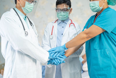 Midsection of doctors stacking hands outdoors