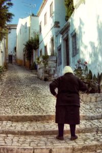 Rear view of woman walking on street amidst buildings