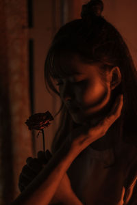 Close-up portrait of woman holding red flower