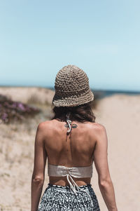 Rear view of woman wearing hat at beach against sky