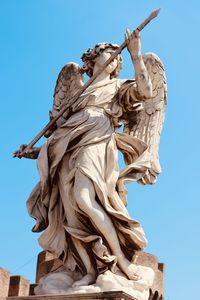 Low angle view of angel statue against blue sky