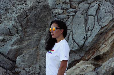 Full length of woman standing on rock against wall