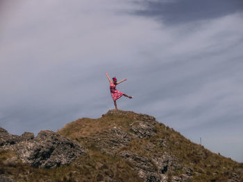 Man standing on rock against sky