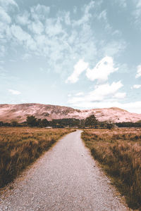 Road amidst field against sky