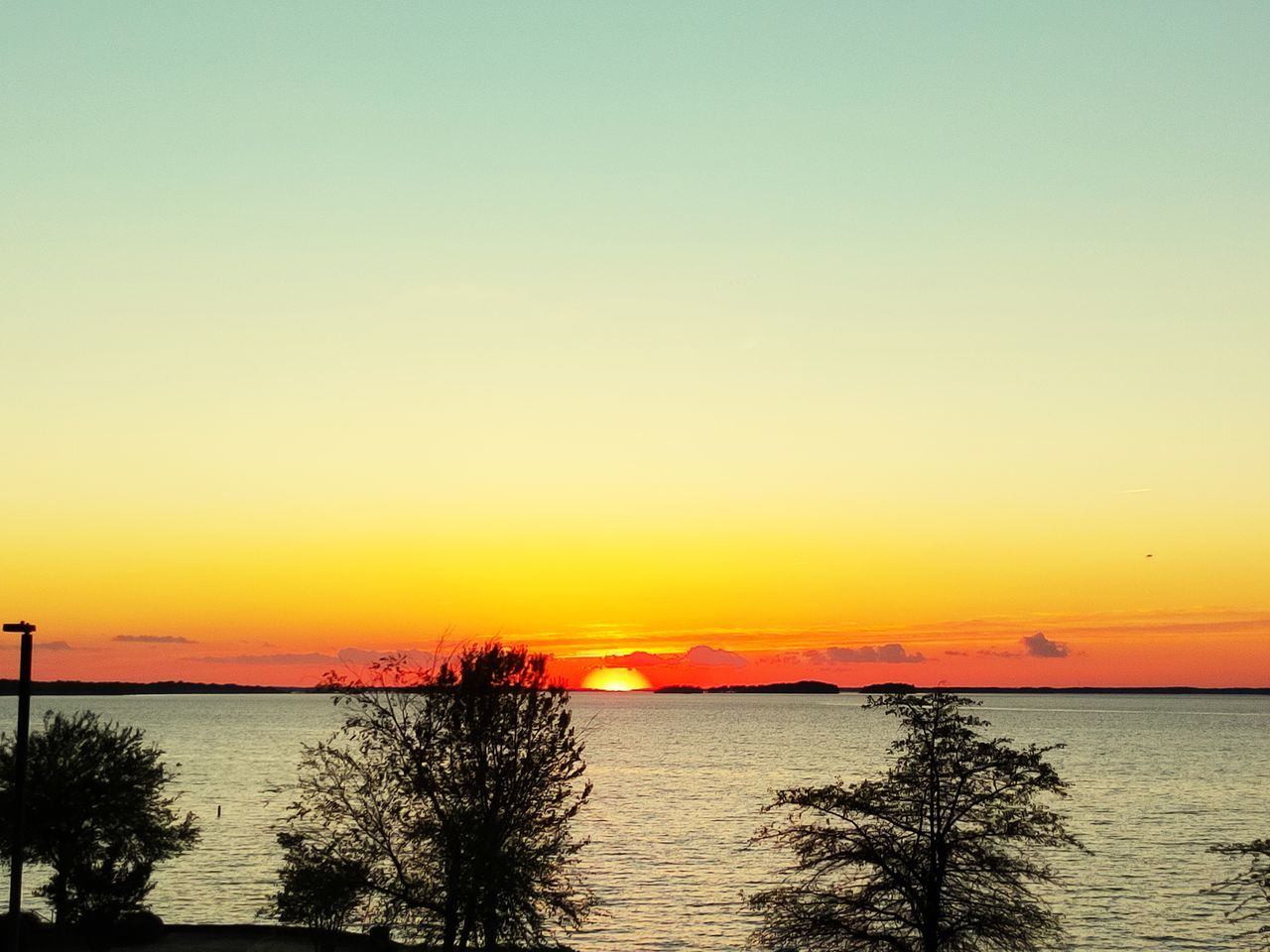 sky, sunset, water, beauty in nature, scenics - nature, sea, tranquility, horizon, tranquil scene, nature, afterglow, orange color, silhouette, horizon over water, dawn, beach, no people, idyllic, ocean, evening, tree, plant, shore, land, red sky at morning, sun, coast, outdoors, copy space, sunlight, non-urban scene, reflection, clear sky
