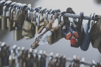 Close-up of figurines on padlocks hanging over string
