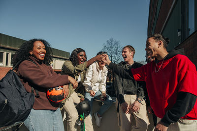 Young man and woman fist bumping while having fun with friends