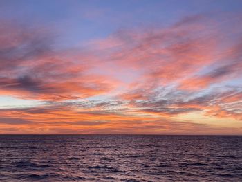 Scenic view of sea against dramatic sky during sunset