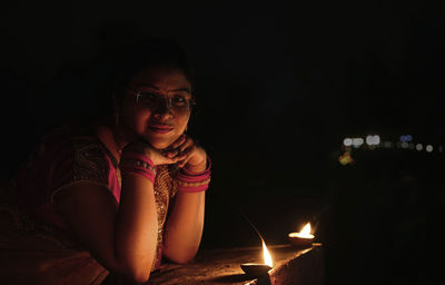 Portrait of woman by illuminated diyas at night