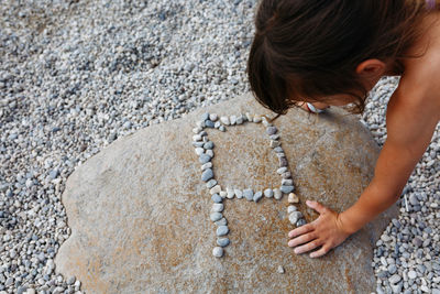 Close up view on child arm and hand making letter a on big stone