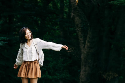 Young woman standing against trees