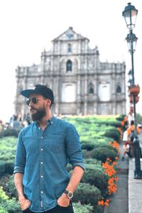 Young man looking away while standing against building