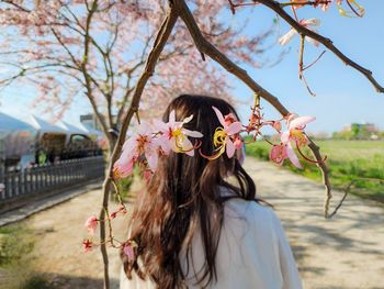 Side view of young woman standing against sky