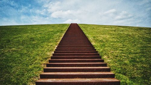 Boardwalk on field against sky